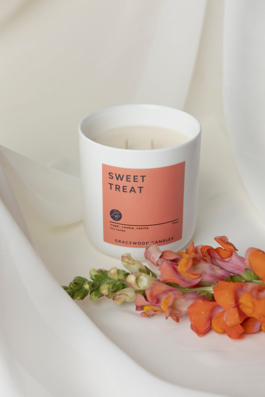 Candle labeled 'Sweet Treat' with flowers on a white surface