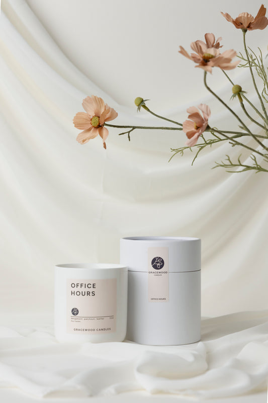 Two candles with labels on a white fabric background with flowers.