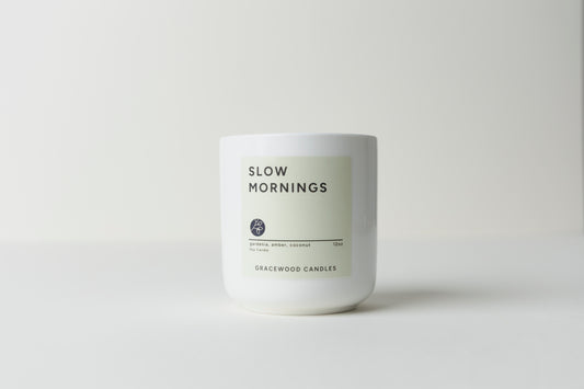 White candle with 'Slow Mornings' label on a light gray background