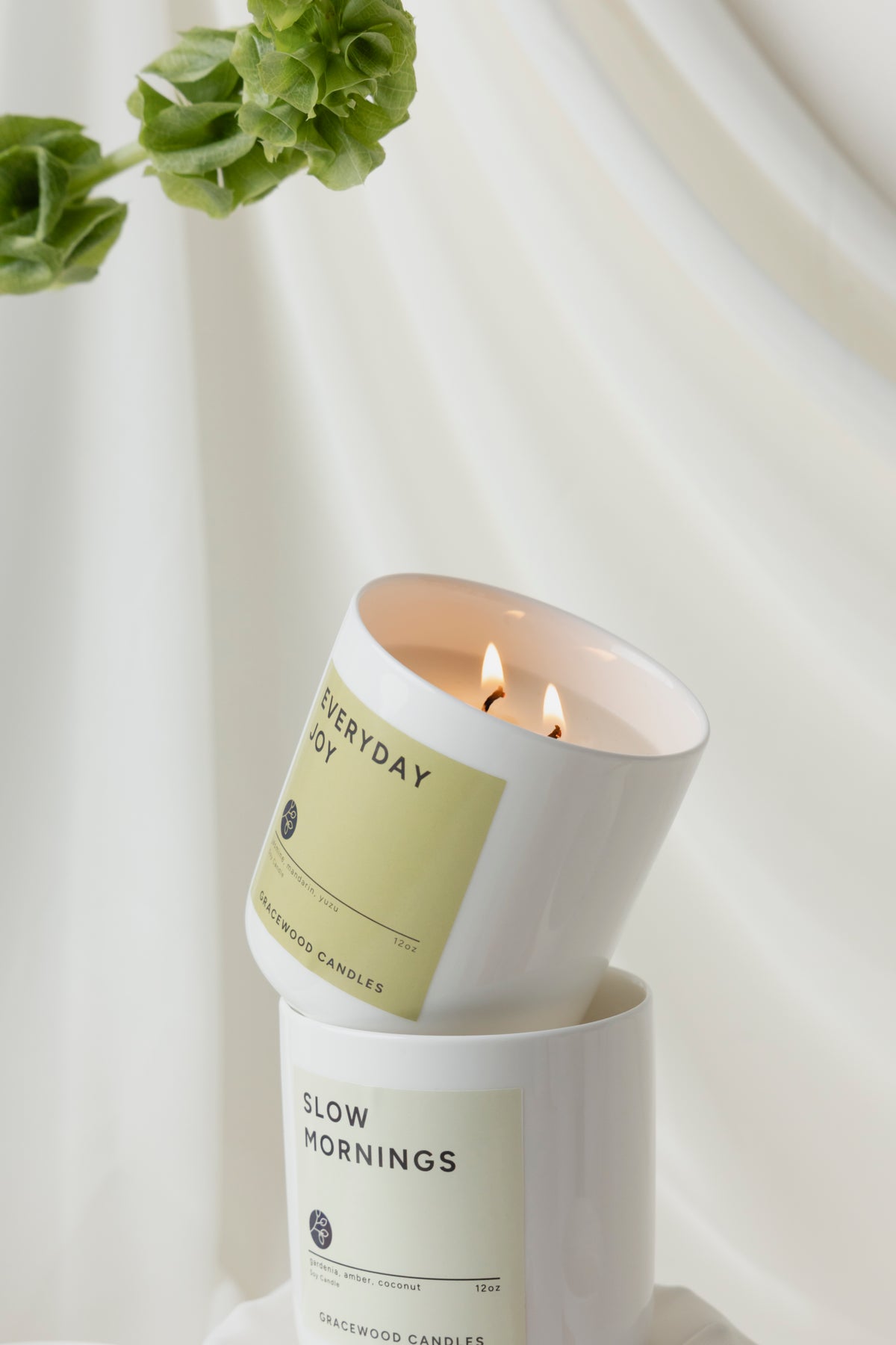 Two candles from Gracewood Candles with greenery in the background