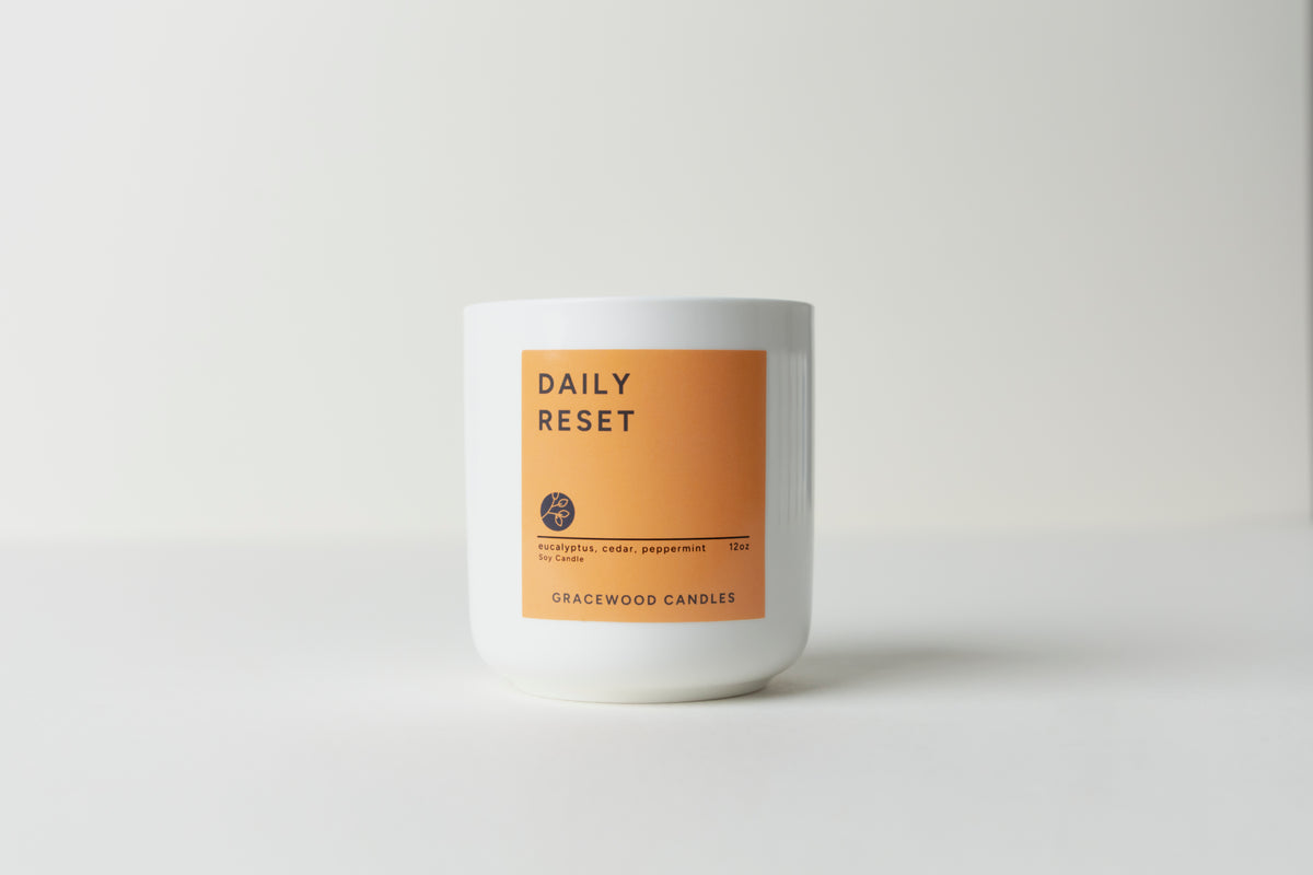 Candle with 'Daily Reset' label on a white background