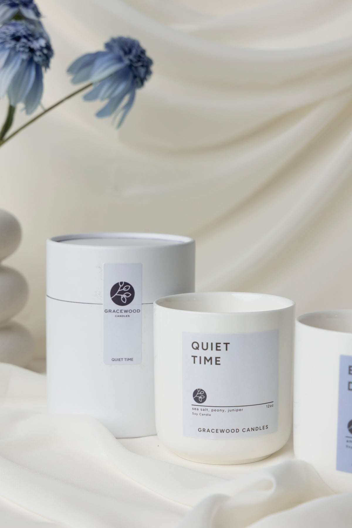 Candle labeled 'Quiet Time' by Gracewood on a white fabric background with blue flowers.