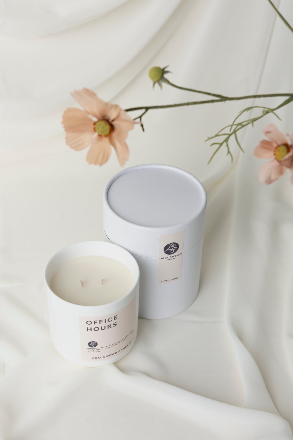 Two candles labeled 'Office Hours' on a white fabric background with flowers.